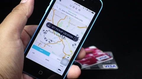 UBER user opening the UBER app on  his iPhone with credit cards visible Stock Footage 56435731