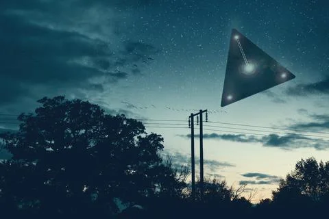 UFO concept. A flying triangle floating above the countryside at night. Stock Photos
