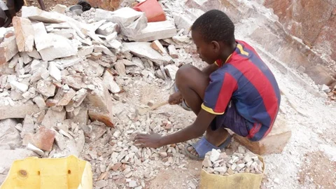 A Ugandan boy breaking rocks into small slabs in a quarry. 스톡 동영상 96463080