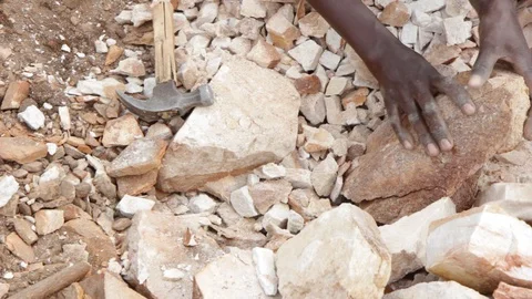 A Ugandan boy breaking rocks into small slabs in a quarry. 스톡 동영상 96463124