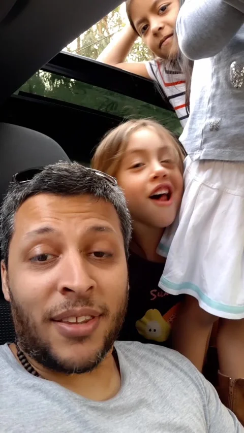 UGC style video of Hispanic father vlogging in car while young daughters stand Video stock 346510285