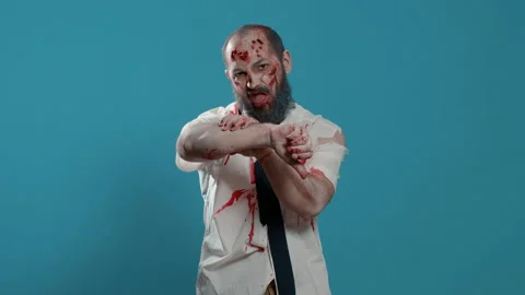 Ugly spooky mindless zombie giving thumbs down hand sign while standing on blue Stock Footage 220312341