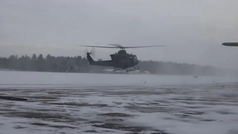 UH-60 Black Hawk helicopter kicking up a snowstorm during takeoff from airfield Stock Footage 299900713