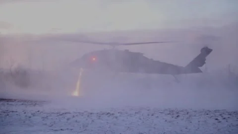 UH-60 Black Hawk kicks up a snowstorm while landing with snow skids at dusk Stock Footage 299233876
