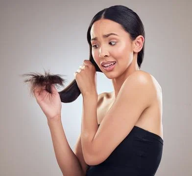 Uh oh Split ends. an attractive young woman holding her hair and looking worried Stock Photos