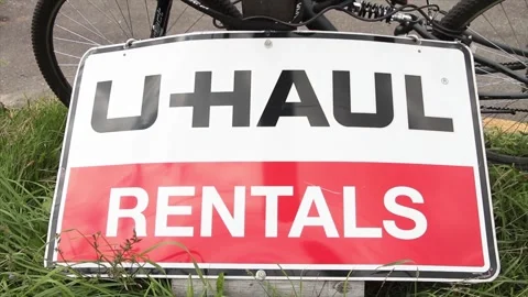 Uhaul rentals rectangle horizontal sign on grass leaning against a post Stock Footage 248714613
