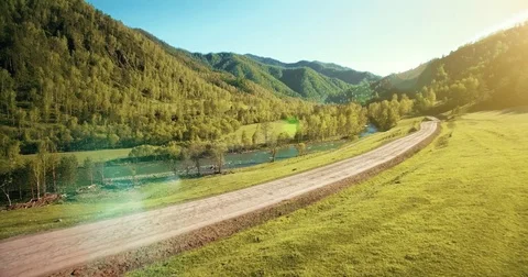 UHD 4K aerial view. Low flight over fresh cold mountain river, meadow and road Stock Footage