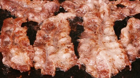 UHD shot of delicious thin sliced bacon frying on the iron pan Видео 95282604