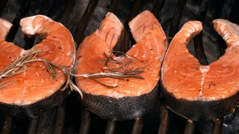 UHD slow dolly of three salmon steaks on the grill Видео 94660641