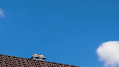 UHD. Timelapse of blue sky and flying clouds above house's roof Stock Footage 204873967