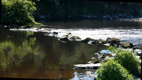UHD29.97Stream flowing over rocks in summer with sunlight glinting on water Stock Footage 113073512