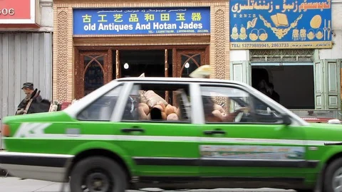Uighur man leans on donkey cart full of butternut vegetables outside jade shop  Stock Footage