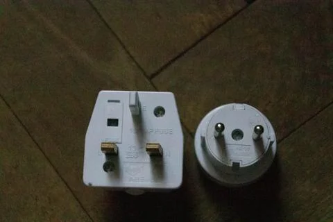 UK and EU plug adapter top view on wood background Stock Photos