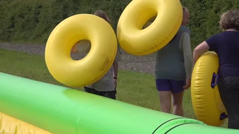 UK: Ed Davey rides down waterslide in rubber ring near Frome, Somerset Stock Footage 276616271