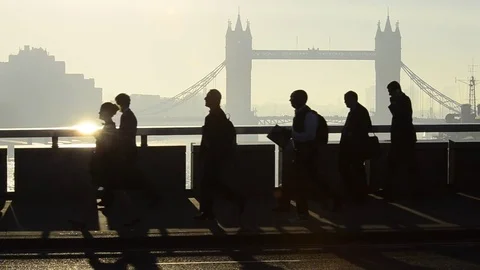 UK, England, London, Commuters crossing London Bridge, Tower Bridge beyond Stock Footage