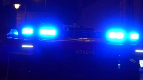 A UK Fire Engine moving slowly with blue lights flashing at night Stock Footage 303661002