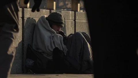 UK January 2017 - A homeless man sits huddled under a blanket as pedestrians Stock Footage