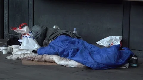 UK January 2019 - People walk past a homeless man sleeping on the floor Stock Footage
