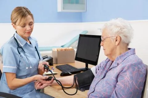 UK nurse taking senior woman's blood pressure Stock Photos