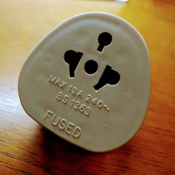 UK Plug standard white on top of wooden table. Converter. Adaptador. Tomada  Stock Photos