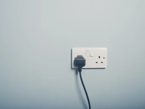 UK wall socket and cord on blue wall Stock Photos