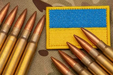 Ukraine flag patch and ammunition placed on military camouflage fabric. Stock Photos