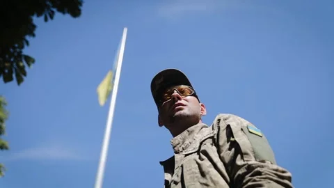 Ukrainian army man standing under the large blue and yellow Ukrainian flag Stock Footage 265898415