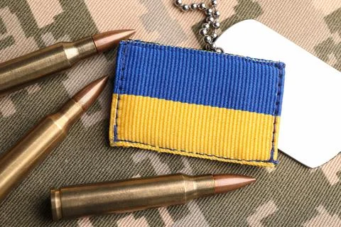 Ukrainian army patch, bullets and ID tags on pixel military camouflage, fla.. Stock Photos