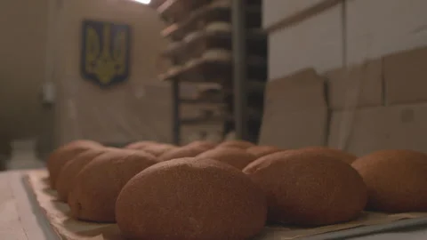 Ukrainian baker puts a tray with hot fresh buns on the table Stock Footage 231339004
