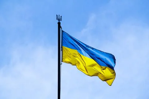 Ukrainian flag in the rays of the rising sun on a background of sky. Bicolor Stock Photos