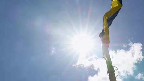 Ukrainian flag waving on flagpole against blue sky and bright sun Stock Footage 336559486