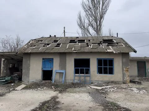 Ukrainian house destroyed by shells with broken windows and a slate roof slashed Stock Photos