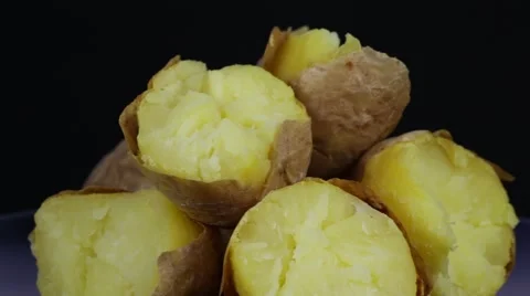 Ukrainian national dish is baked potatoes. Potato on a black background rotates Stock Footage