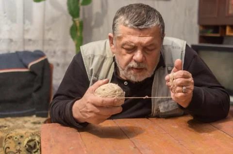 Ukrainian peasant taking clew of thread while  sitting at old table Stock Photos