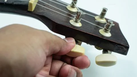 Ukulele with 4 strings being tuning on a white background Stock Photos