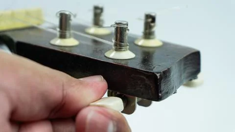Ukulele with 4 strings being tuning on a white background Stock Photos