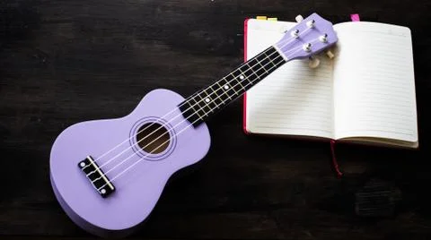 The ukulele and opened book put on wooden desk Stock-Fotos