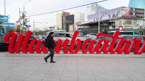 Ulaanbaatar Mongolia: Men Walking Past Red City Name Sign &amp; Rental Scooters - Stock-Footage 328386990
