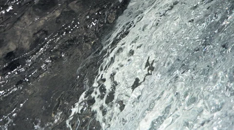 Ultra-slow motion silvery water flowing down a rock face Stock Footage