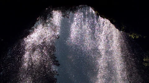 Ultra-slow motion sunny waterfall viewed from a grotto behind the falls Stock Footage 59546476