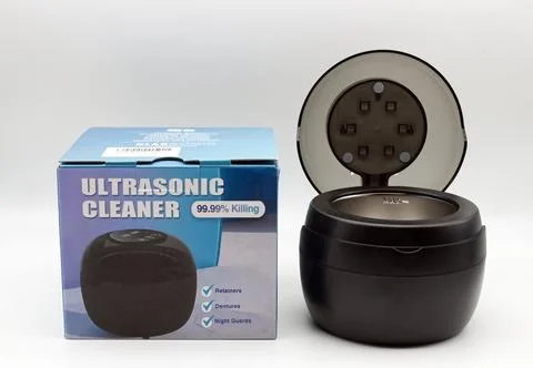 Ultrasonic cleaner device displayed next to its retail packaging box. Stock Photos