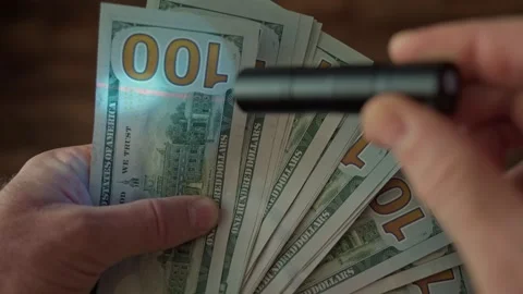 An ultraviolet flashlight illuminates dollar bills to verify authenticity Vidéo 342125185
