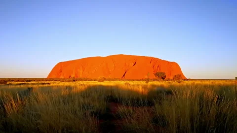 Uluru glows orange at sunset in the Australian Outback. Vídeos de archivo 338026664