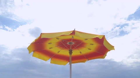 Umbrella on the beach fluttering in the wind, cloudy sky. Stock Footage 161134160