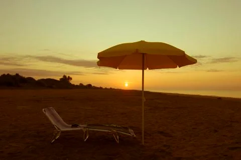 Umbrella on the beach at sunset Stock Photos