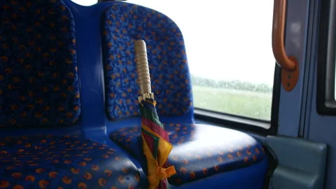 An umbrella left and lost on a blue patterned seat inside a bus, with Stock Footage 283383599