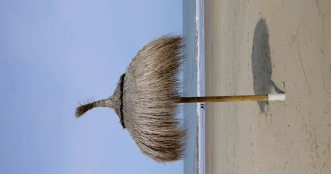 An umbrella made of straw on a sandy beach on the sea. Vertical video. Video stock 241511802