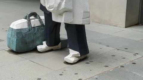 Umbrella man stone statue tilt up artwork city street Stock Footage 218224717