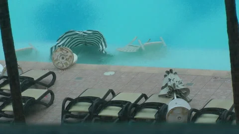 Umbrellas and chairs fall in pool during storm Stock Footage 183088368