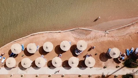 Umbrellas, deck chairs and tourists relaxing on the beach. Aerial top view. Stock Footage 85281957